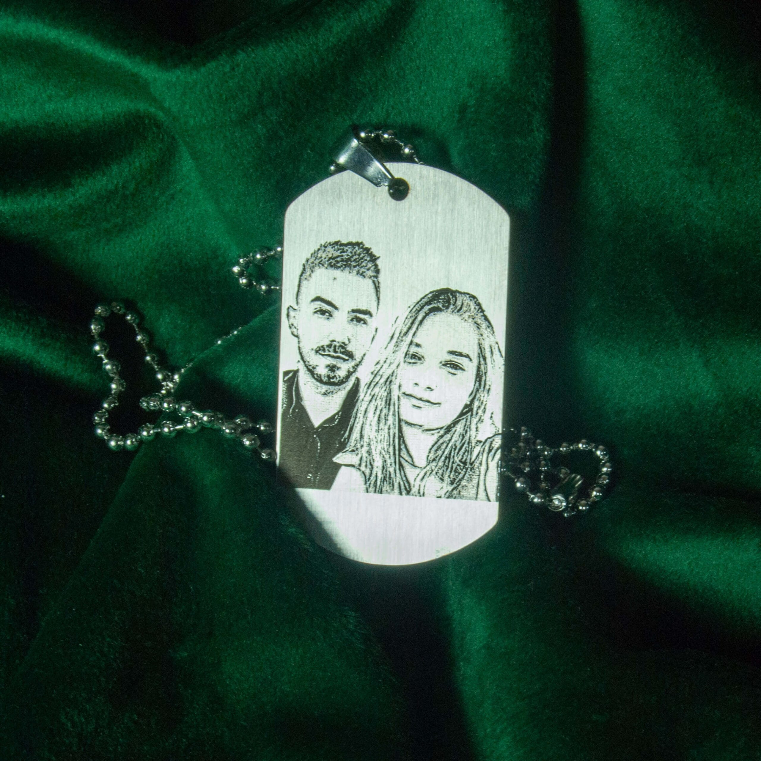 Imaginea prezintă un lanț elegant din oțel inoxidabil cu pandantiv rotund. Pe pandantiv este gravată o fotografie personalizată și textul ales de client, ambele realizate printr-o gravură laser de înaltă precizie. Pandantivul este atașat la un lanț subțire cu zale fine, strălucind sub lumina blândă care accentuează detaliile fine ale gravurii.